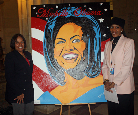 Sherry Cloud and Jacqueline Muhammad from Cleveland Hopkins Airport flank painting of Michelle Obama