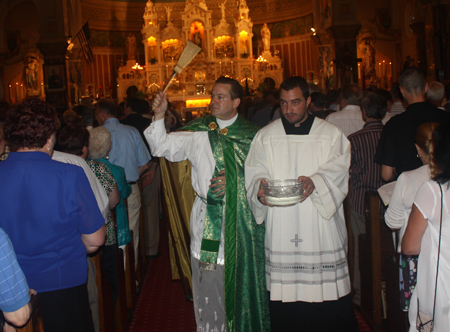Father Eric Orzech, new pastor of St Casimir Church in Cleveland blesses with holy water