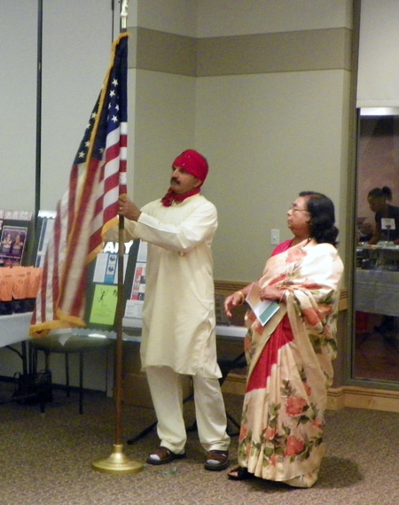 Michael Sreshta and Mrs. Subha Sen-Pakrashi unfurl the US Flag