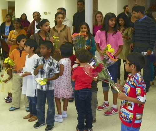 Indian American children bring flowers to the statue of Mary