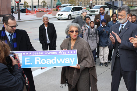 Gloria Owens with street sign for her father Jesse Owens