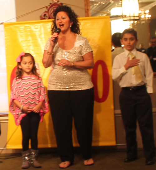 Amy George and children sing the National Anthem
