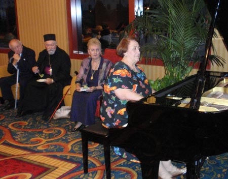 Olga Gradojevic, professor at the Cleveland Institute of Music, plays the piano at the reception as her husband Mr. Vojin Gradojevic, Reverend Vasilije Sokolovic and his wife Zagorka Sokolovic watch.