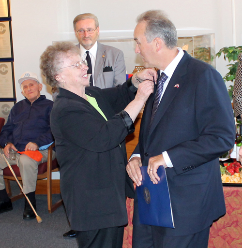 Slovenian Woman of the Year Alice Kuhar pins special awards on the lapels of Slovenian Ambassador Roman Kirn 