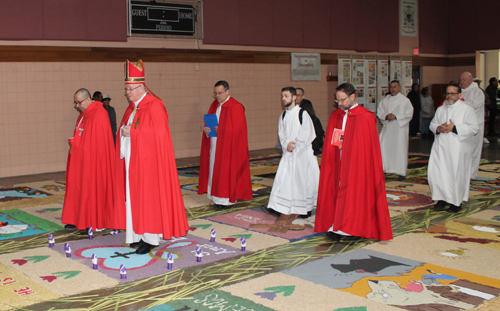 Bishop Woost walks over the Holy Week carpets