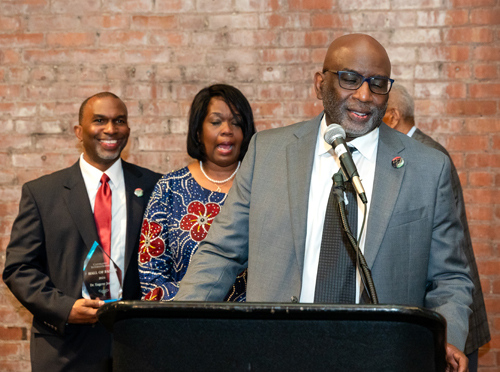 Rev Moss Jr. inducts Dr. Eugene Jordan with his children on stage