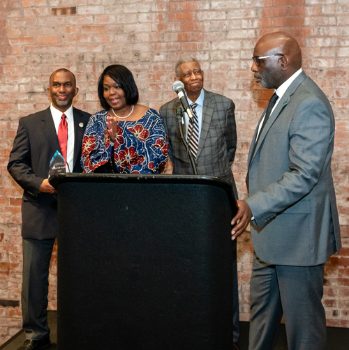 Rev Moss Jr. inducts Dr. Eugene Jordan with his children on stage