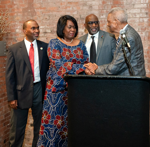 Rev Moss Jr. inducts Dr. Eugene Jordan with his children on stage