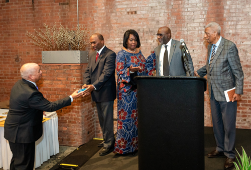 Rev Moss Jr. inducts Dr. Eugene Jordan with his children on stage