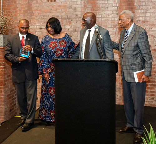 Rev Moss Jr. inducts Dr. Eugene Jordan with his children on stage