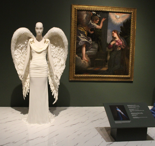 Evening Dress and Wings next to painting of The Annunciation