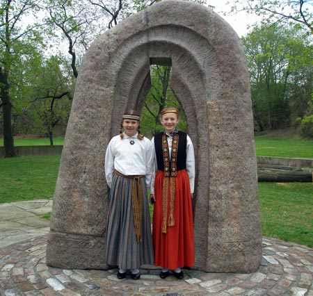 Latvian girls Ariana Dauhss and Laila Kubulias pose at sculpture